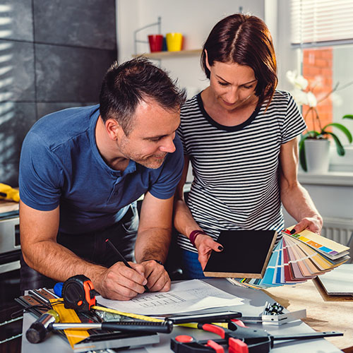 man and woman planning their home renovation with blueprints and swatches