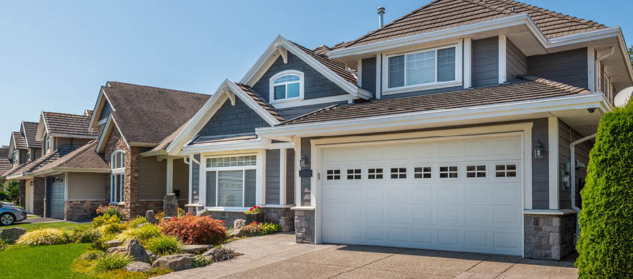 exterior view of a home with gray siding pleasant landscaping and garage